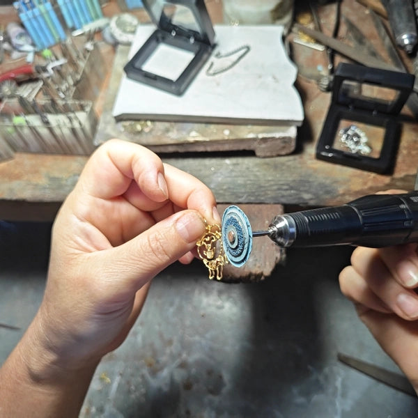 Artisan hand-polishing and finishing a custom jewelry pendant